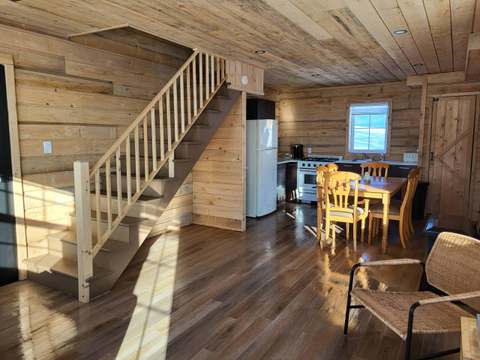 View of the open concept area featuring the kitchen, dining room, and staircase of the Hibou cabin.