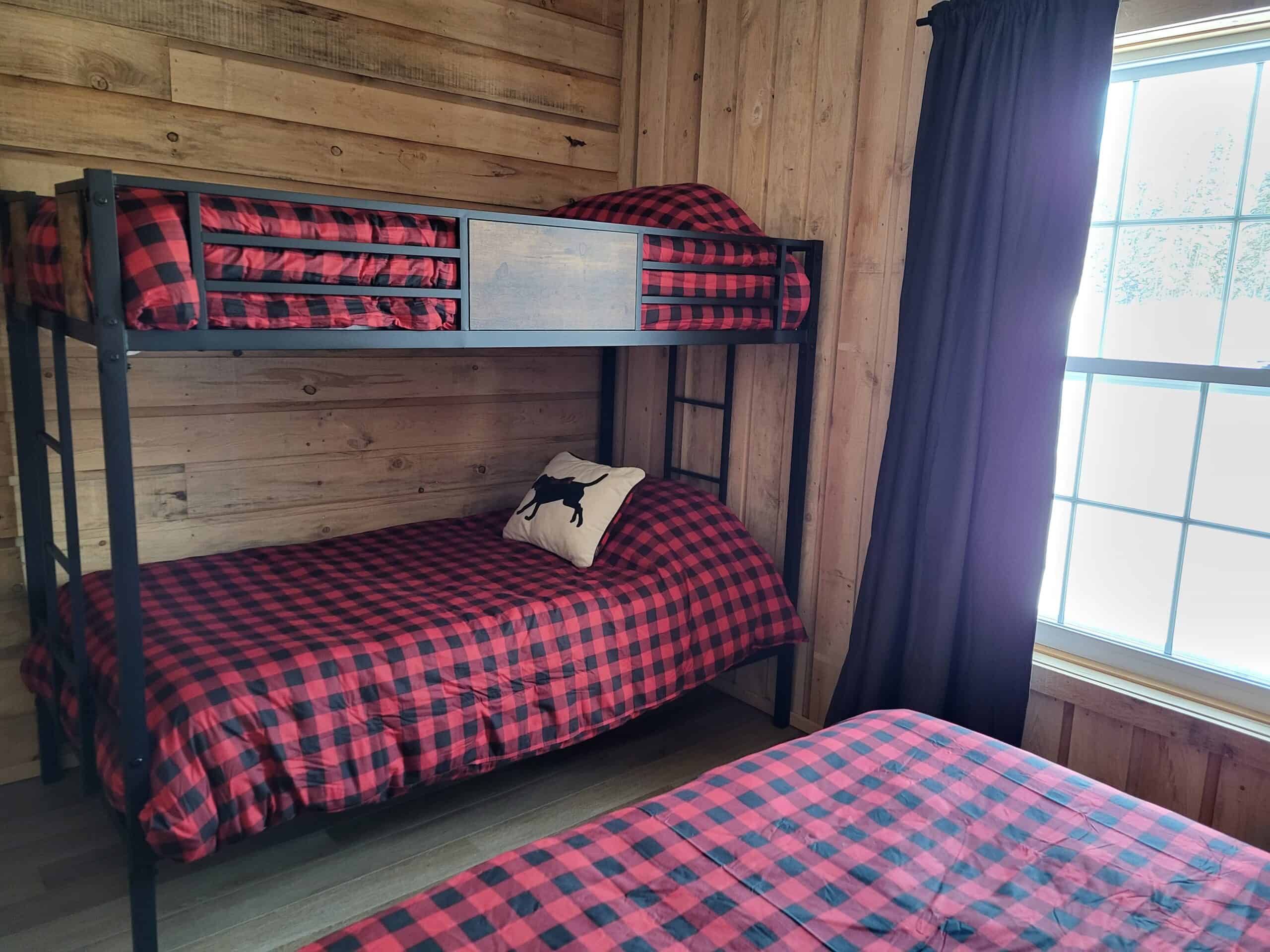 This bedroom features bunk beds with red and black plaid bedding.