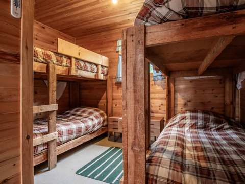 Cette chambre rustique est équipée de lits superposés en bois avec literie à carreaux.