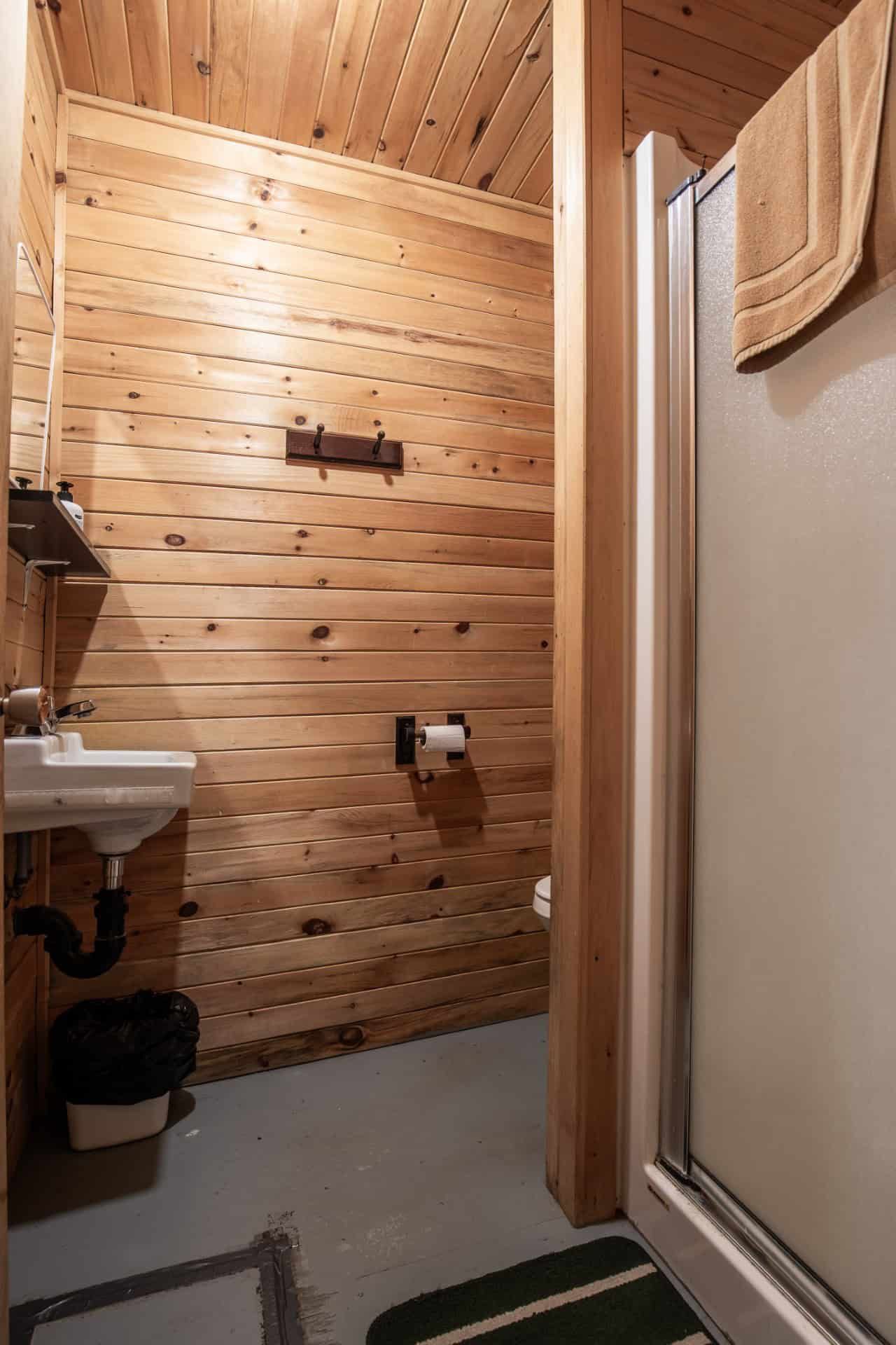 La salle de bain du chalet avec murs en bois, lavabo et douche.