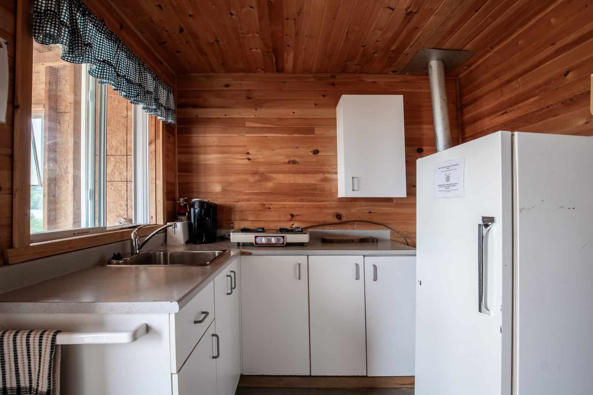 La cuisine équipée du chalet Perdrix comprend un réfrigérateur, une plaque de cuisson et un évier.