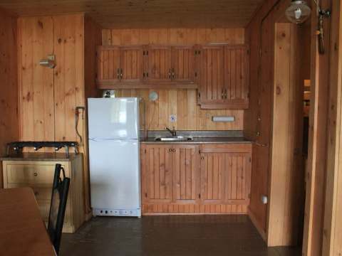 La cuisine équipée du chalet comprend un réfrigérateur, un évier et une cuisinière au gaz.