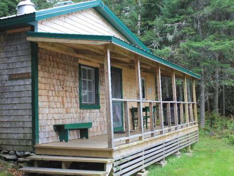Le chalet Champagne dispose d'une galerie couverte avec un coin repas extérieur en forêt.