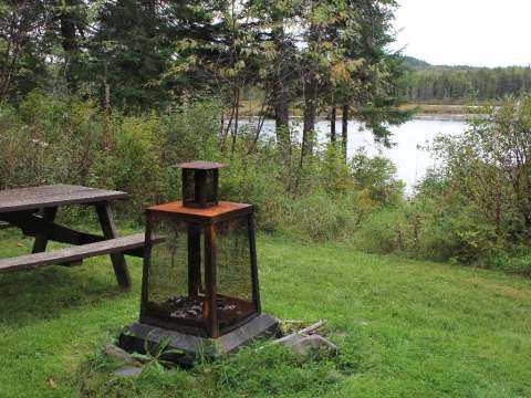 Une table de pique-nique et un foyer extérieur sont installés sur le terrain du chalet.