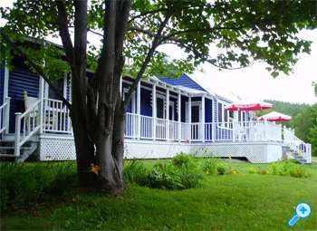 Side view of the Lodge with its long veranda and umbrellas, surrounded by landscaping.