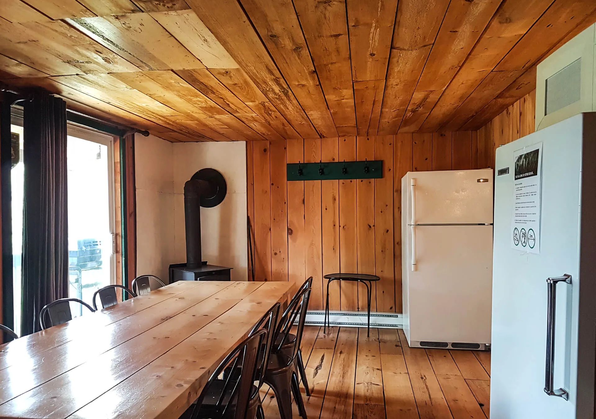 The cottage dining area includes a large wooden table and a wood stove.