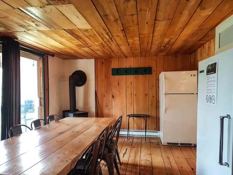 The cottage dining area includes a large wooden table and a wood stove.