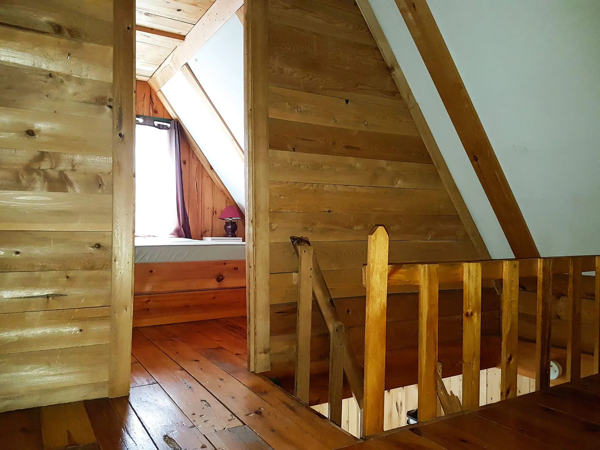 View of the bedroom space located on the wooden mezzanine level of the cabin.