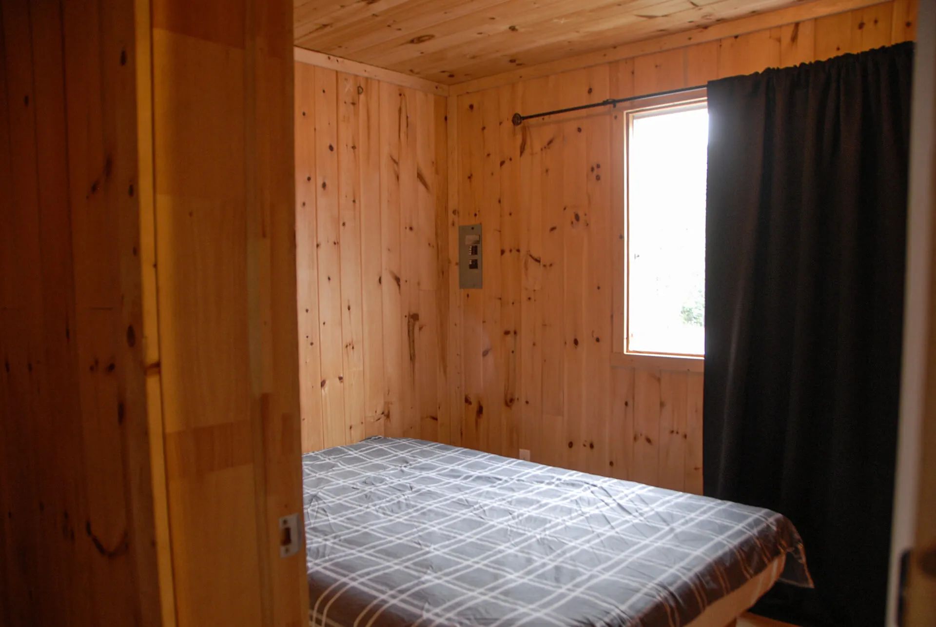A bedroom with a bed and natural wood paneling walls in the cabin.