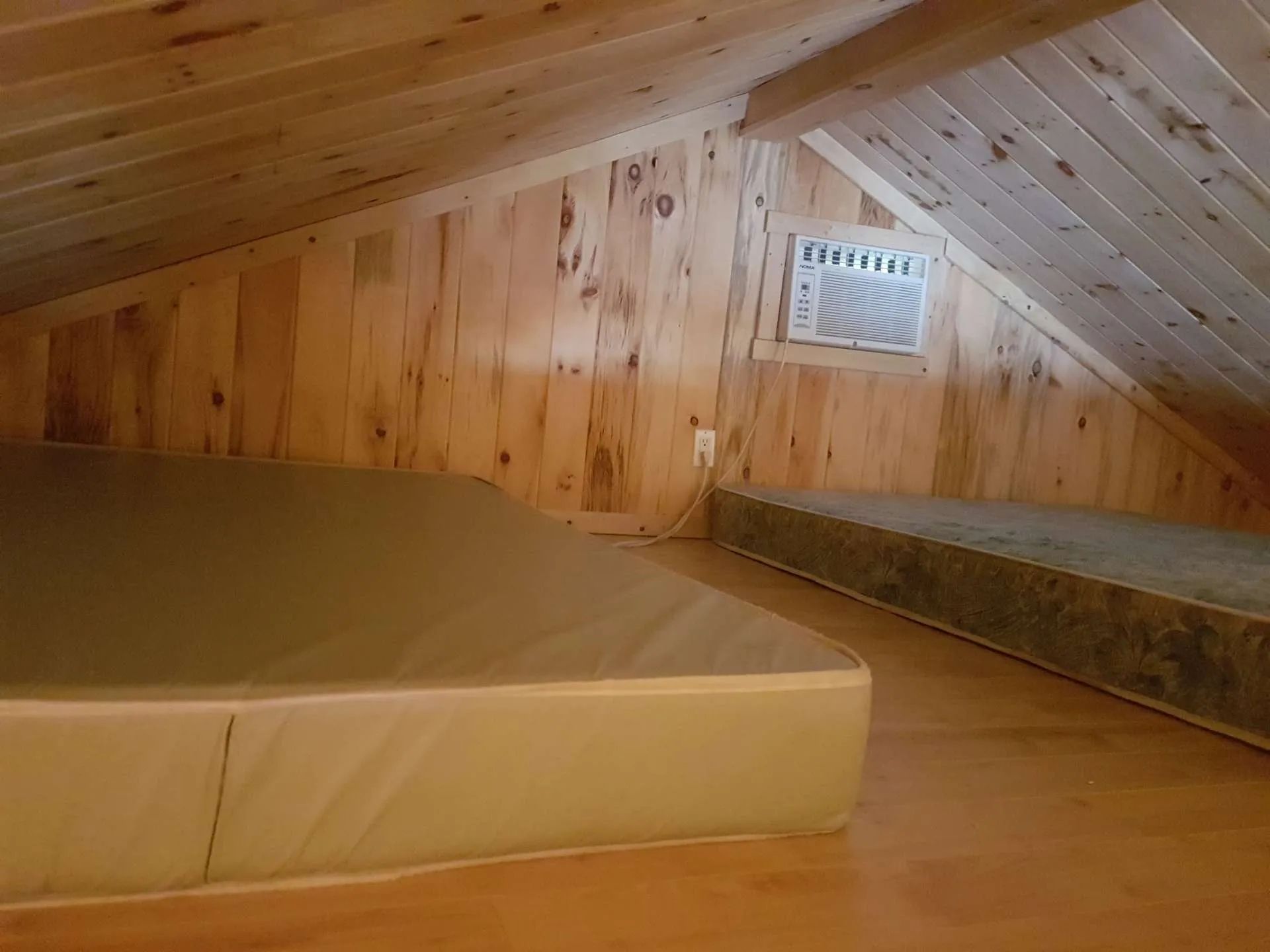 The cabin's loft area features two mattresses under the sloped wooden ceiling.