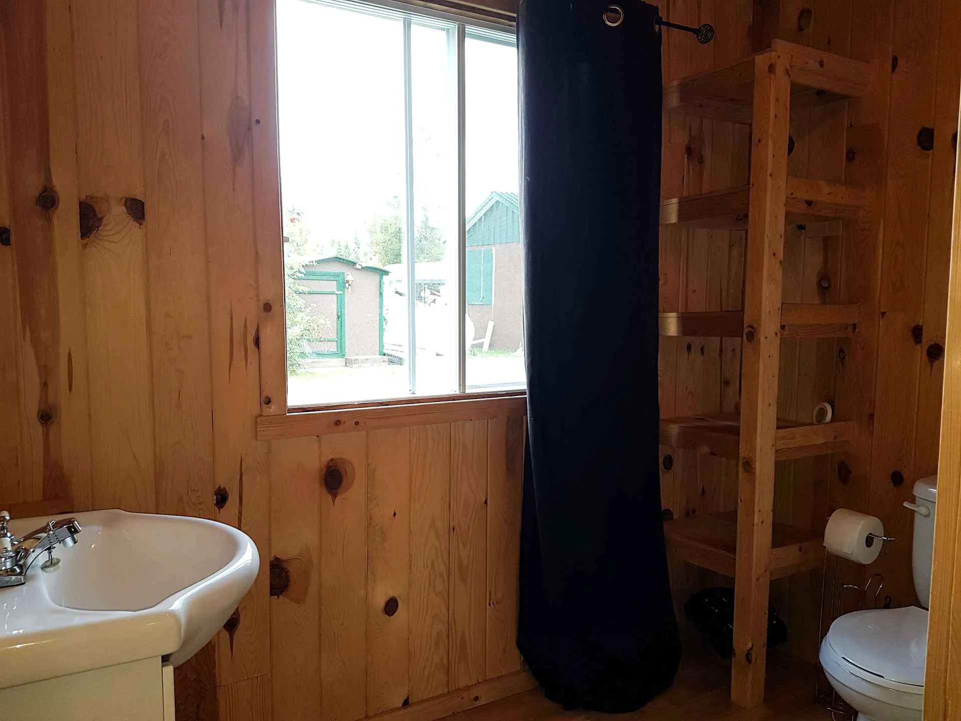 View of the cabin's bathroom with wooden walls and storage shelves.