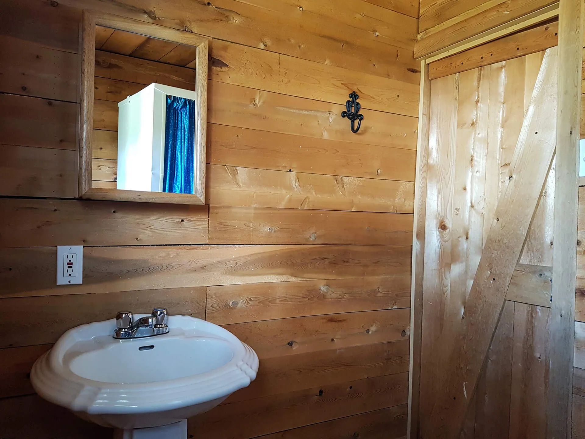 View of the cottage bathroom including a pedestal sink and a mirror.