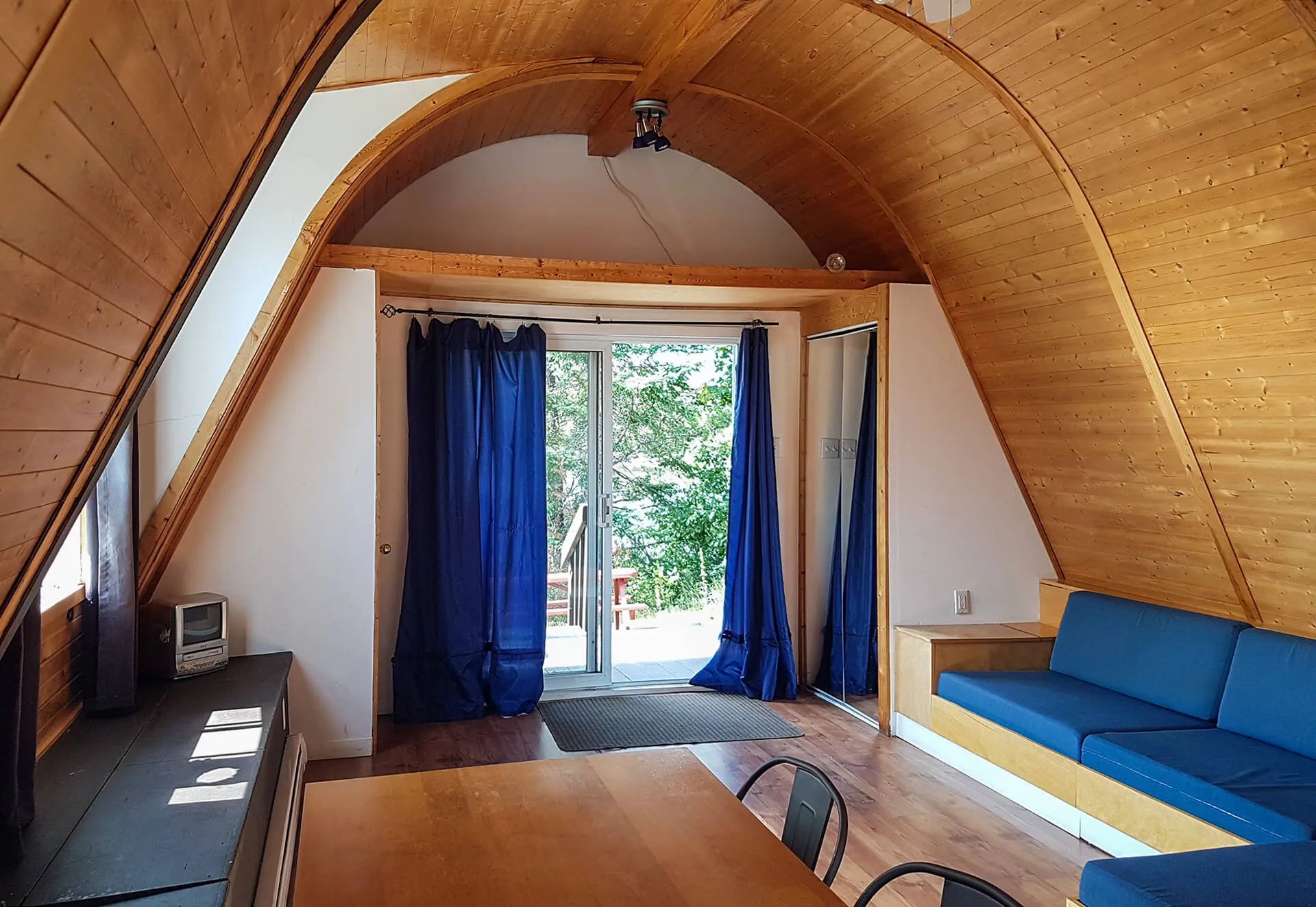 View inside the cabin featuring curved wooden ceilings and a patio door leading outdoors.