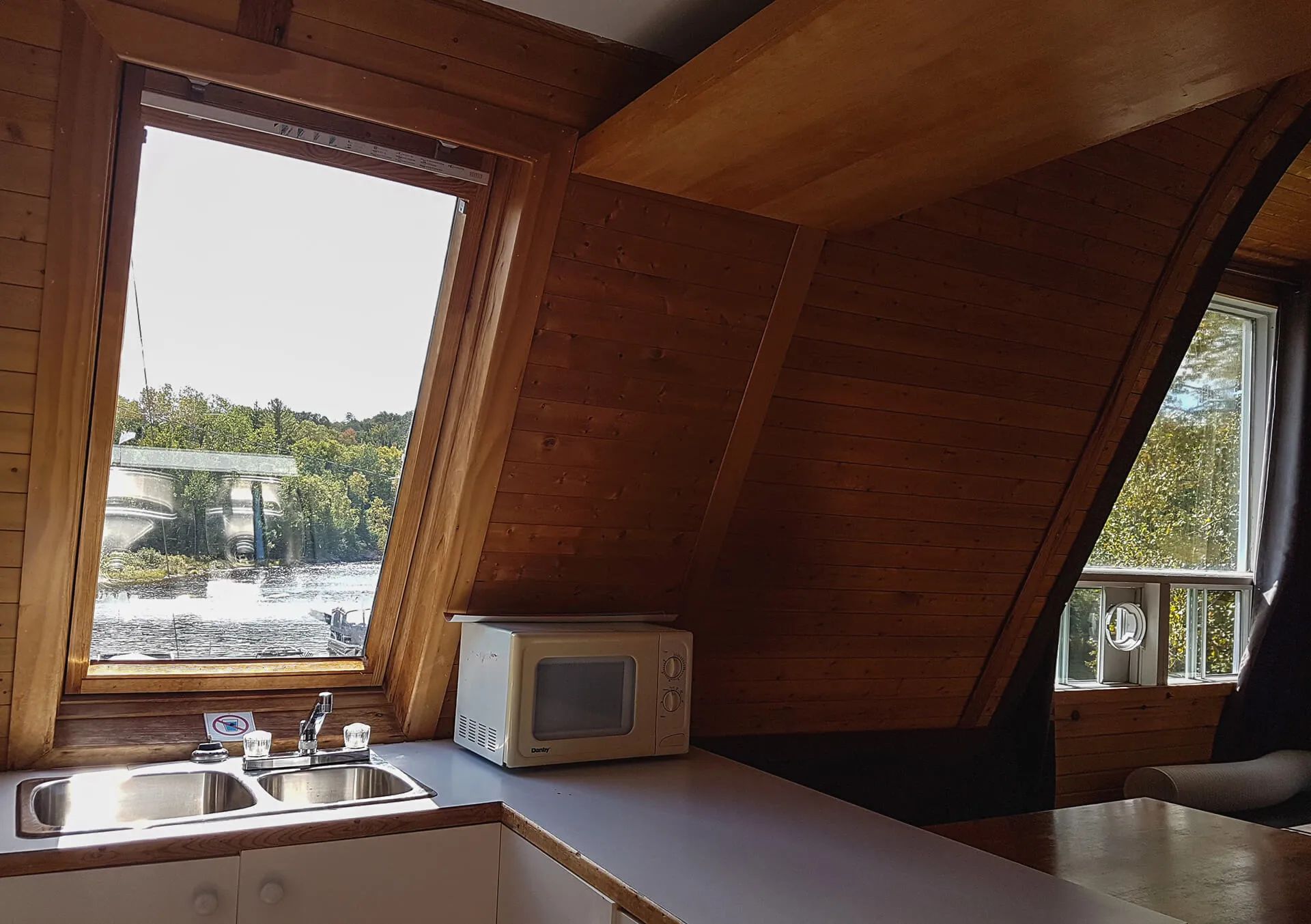 The cottage kitchen offers a view of the water and surrounding trees.