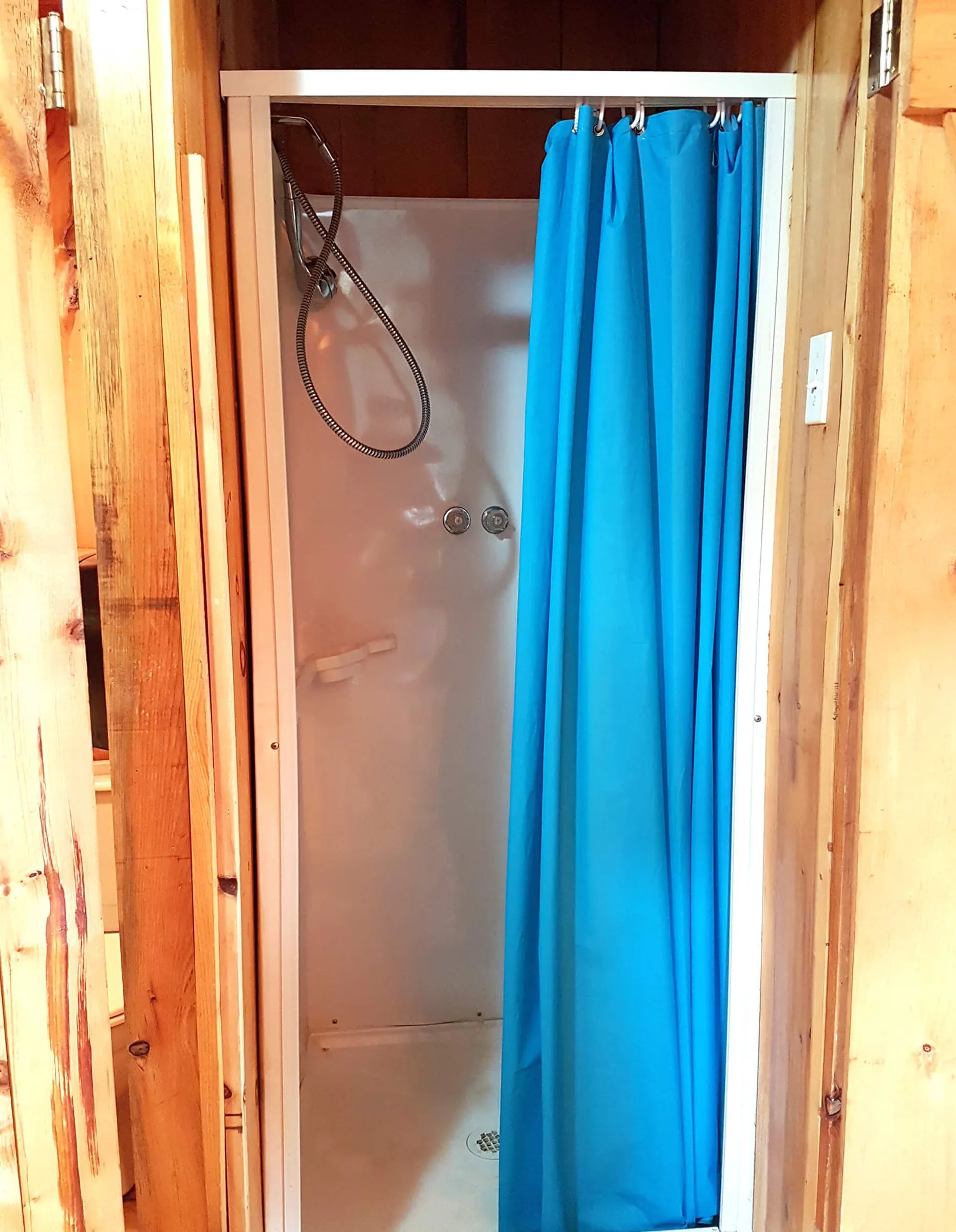 La cabine de douche est aménagée dans une alcôve aux murs en bois de pin.