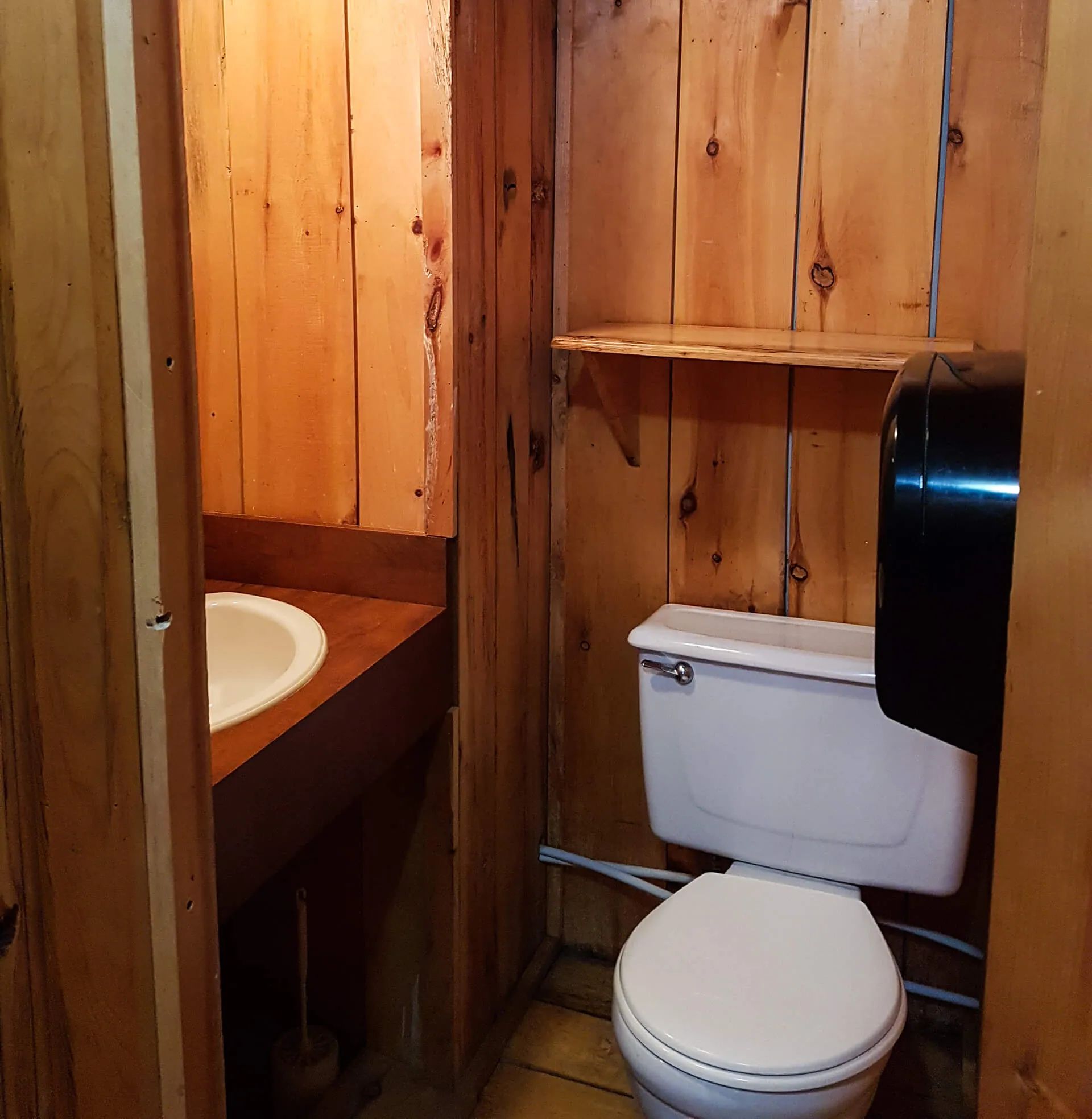 La salle de bain du chalet dispose d'un lavabo et d'une toilette dans un décor en bois rustique.