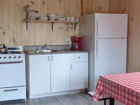 The cottage's equipped kitchen includes a stove, a refrigerator, and a dining table.