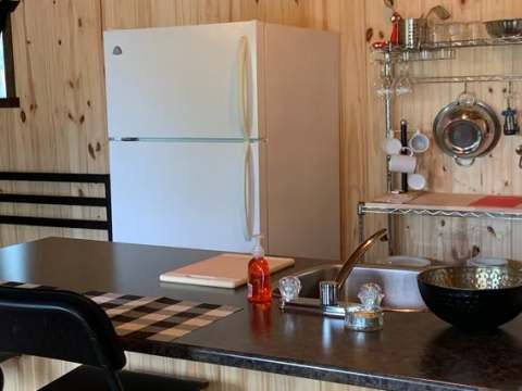 The cottage kitchen is equipped with a refrigerator, a stove, and a counter with seating.