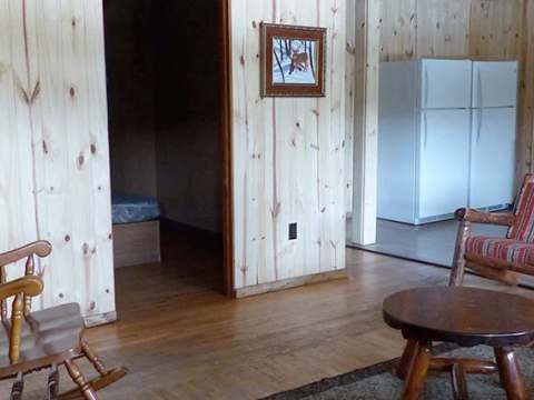 The open area of the cabin features a living area with wooden furniture and an adjacent kitchen.