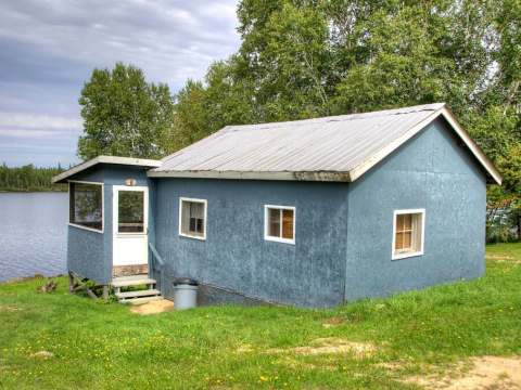 Le chalet numéro 8 est situé en bordure de l'eau, entouré d'arbres et de verdure.