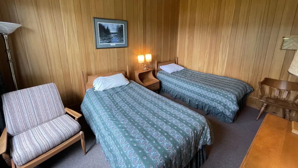 This room at the Manoir offers two single beds in a rustic wood interior.