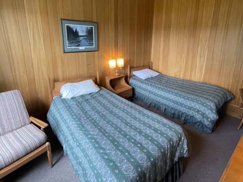 This room at the Manoir offers two single beds in a rustic wood interior.