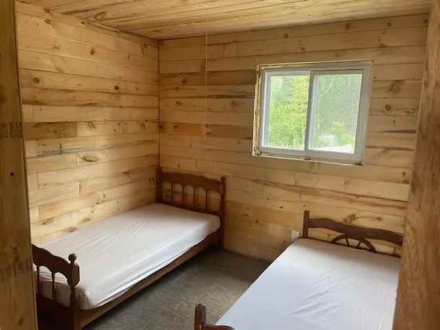 Cette chambre rustique est équipée de deux lits simples avec murs en bois naturel.