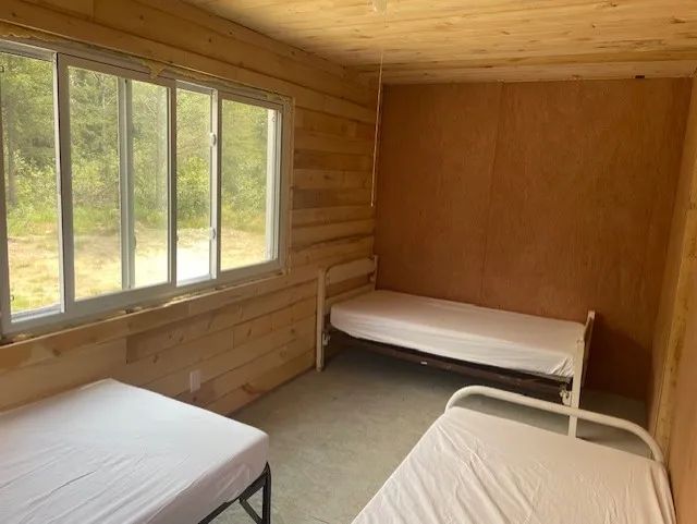 Cette chambre rustique est équipée de plusieurs lits simples et donne sur la forêt.