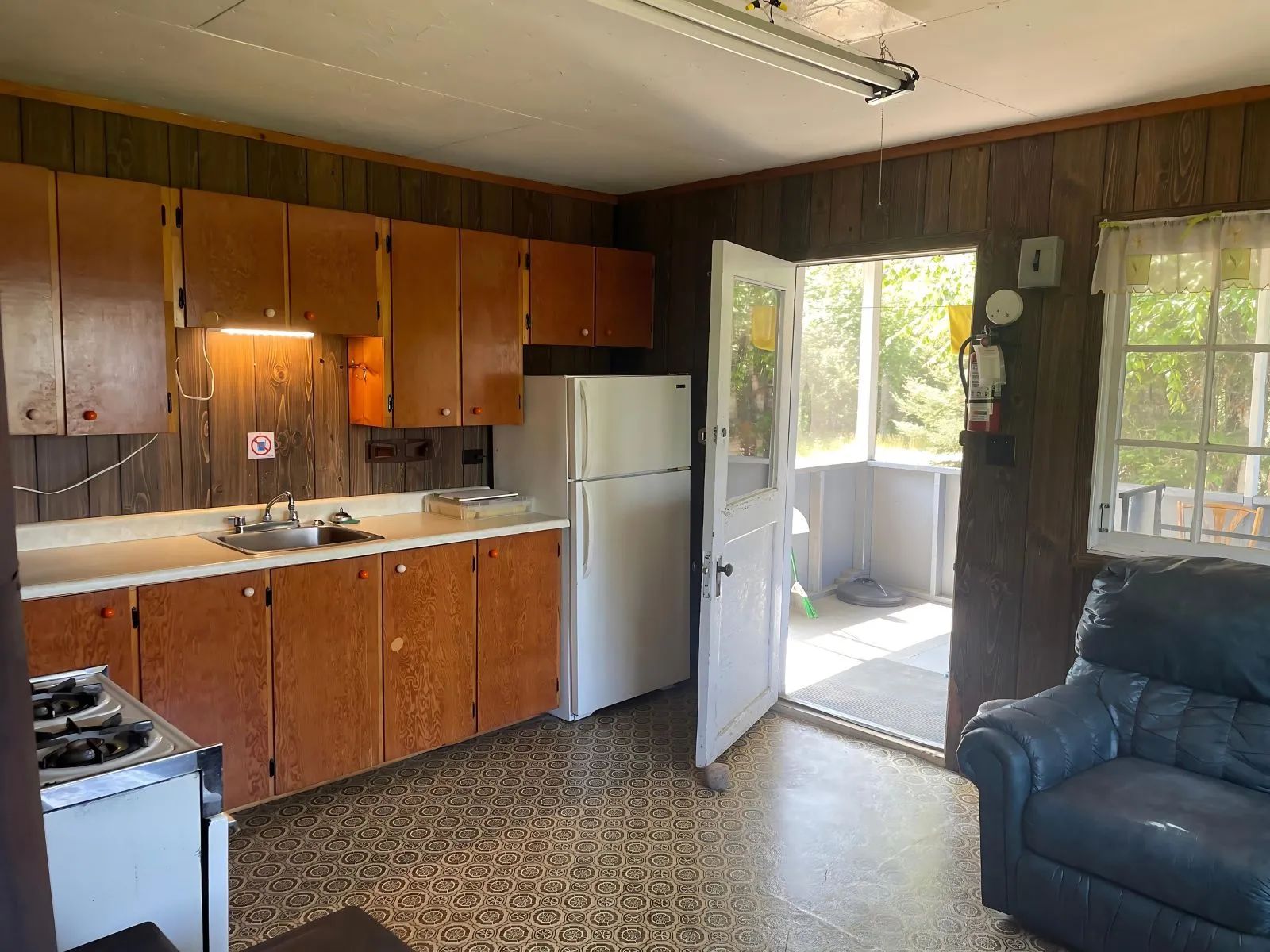 Cette cuisine équipée en bois inclut une cuisinière et un réfrigérateur dans un chalet rustique.