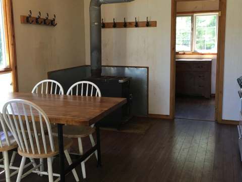 This kitchen features a dining table, a wood stove, and access to another room.