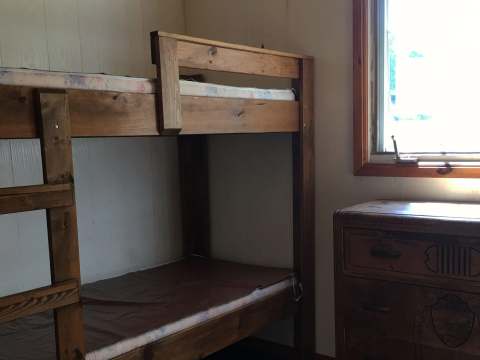 This bedroom at the Alexander cabin features a wooden bunk bed and a dresser.