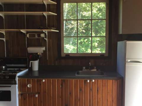 The cottage's functional kitchen includes a stove, a refrigerator, and a sink.
