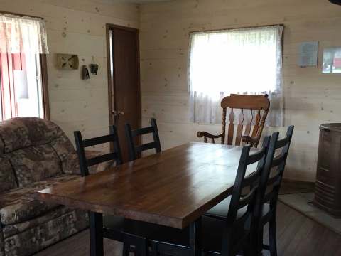 Dining area and living room in a cottage with wooden walls and a slow-burning stove.