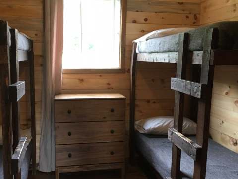 This bedroom features two wooden bunk beds and a storage dresser.