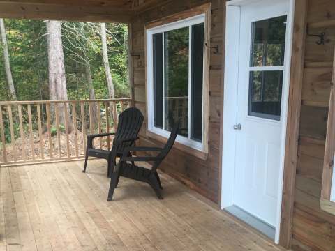 The cottage porch is equipped with two chairs to enjoy the view of the forest.