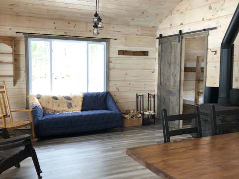 The open-concept living area of the Pauline cabin includes a comfortable living room and a wood stove.
