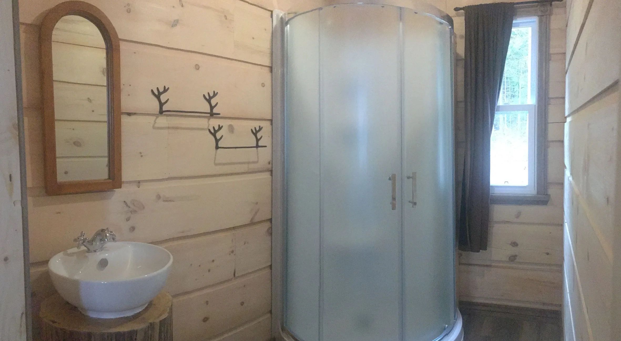 The cottage bathroom features an enclosed shower, a sink, and a mirror.