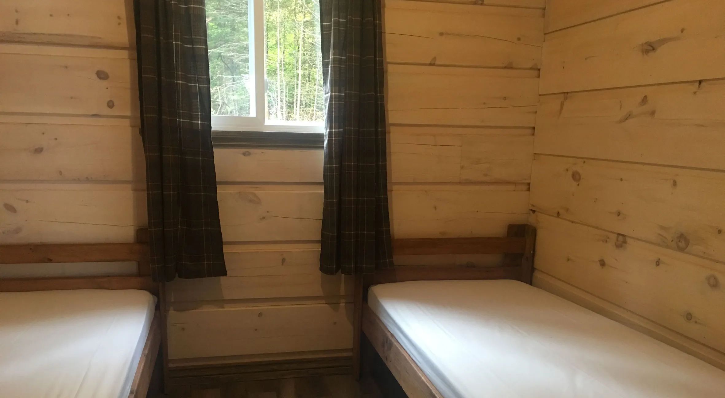 This bedroom features two single beds in a log cabin.