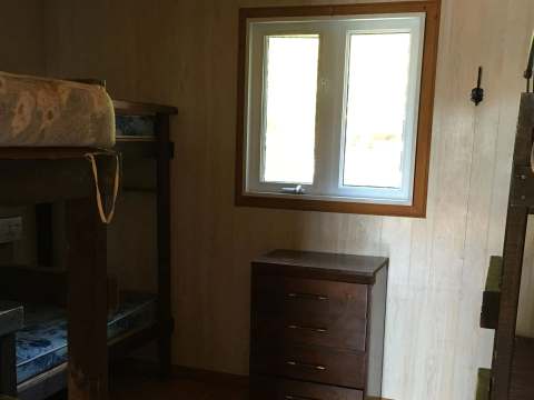 A bedroom with bunk beds and a dresser in the Poliquin cottage.