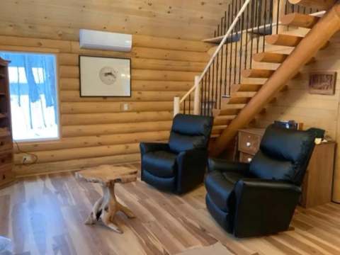Le salon du chalet L'Amer dispose de fauteuils confortables et d'un escalier en bois menant à l'étage.