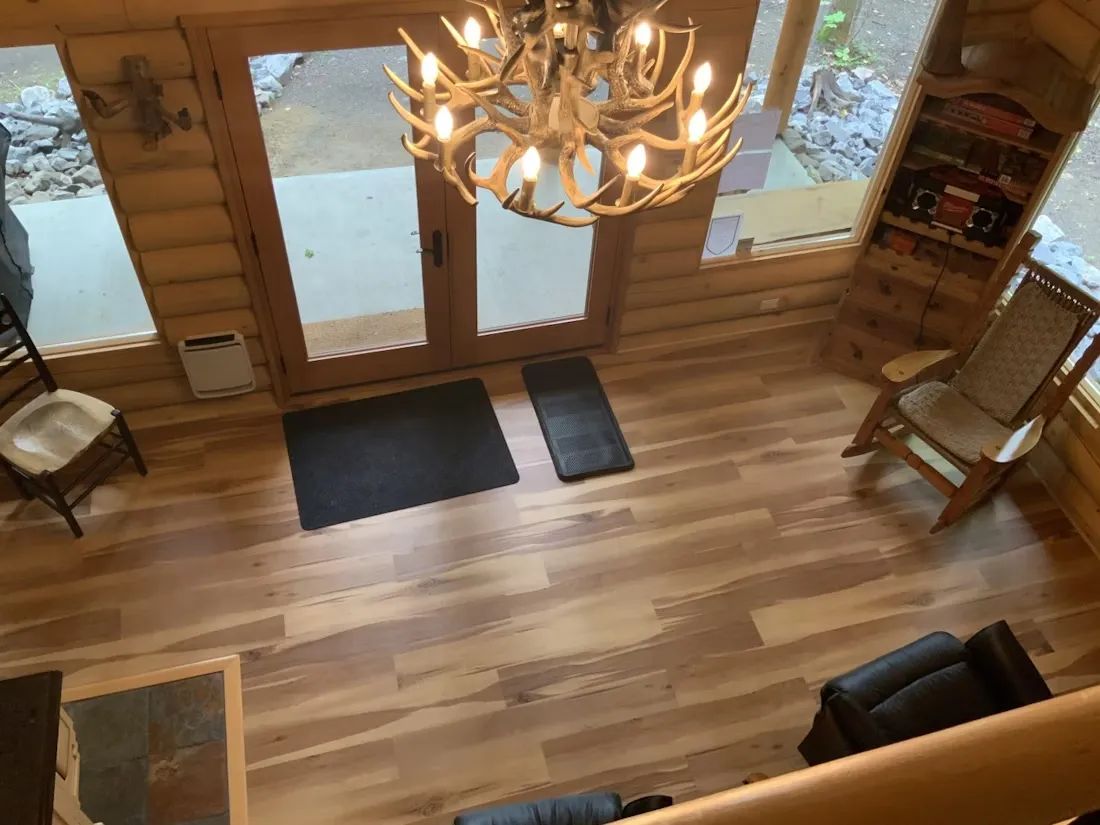 Vue en plongée du salon avec foyer en bois et luminaire en bois de cervidés.