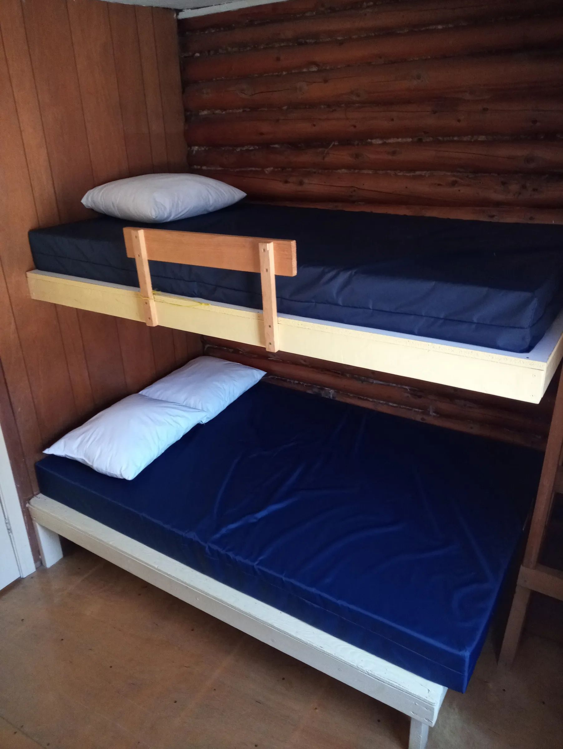 Deux lits simples avec matelas bleu sont installés dans le chalet.