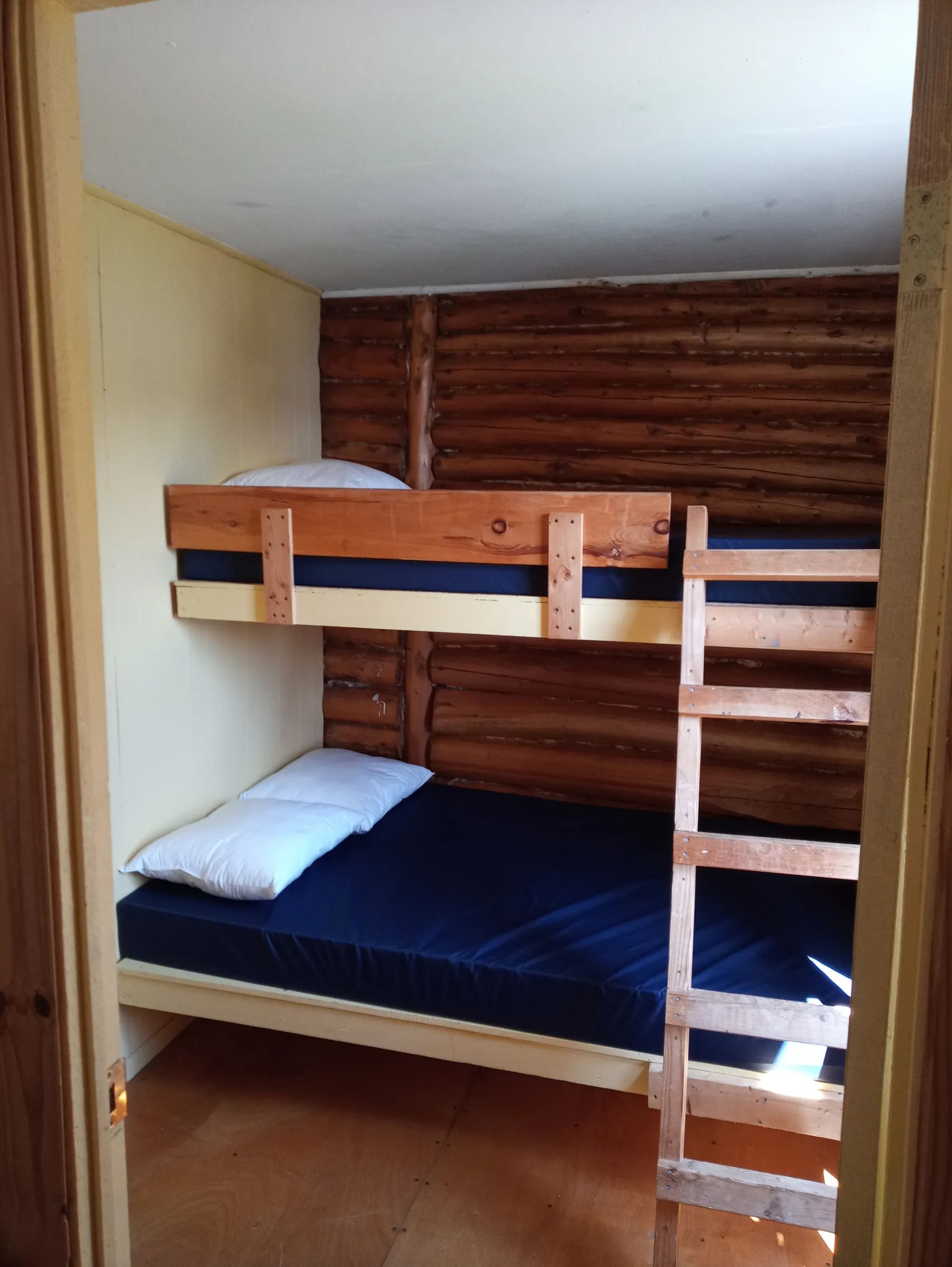 Vue en plongée sur les lits superposés en bois à l'intérieur du chalet.
