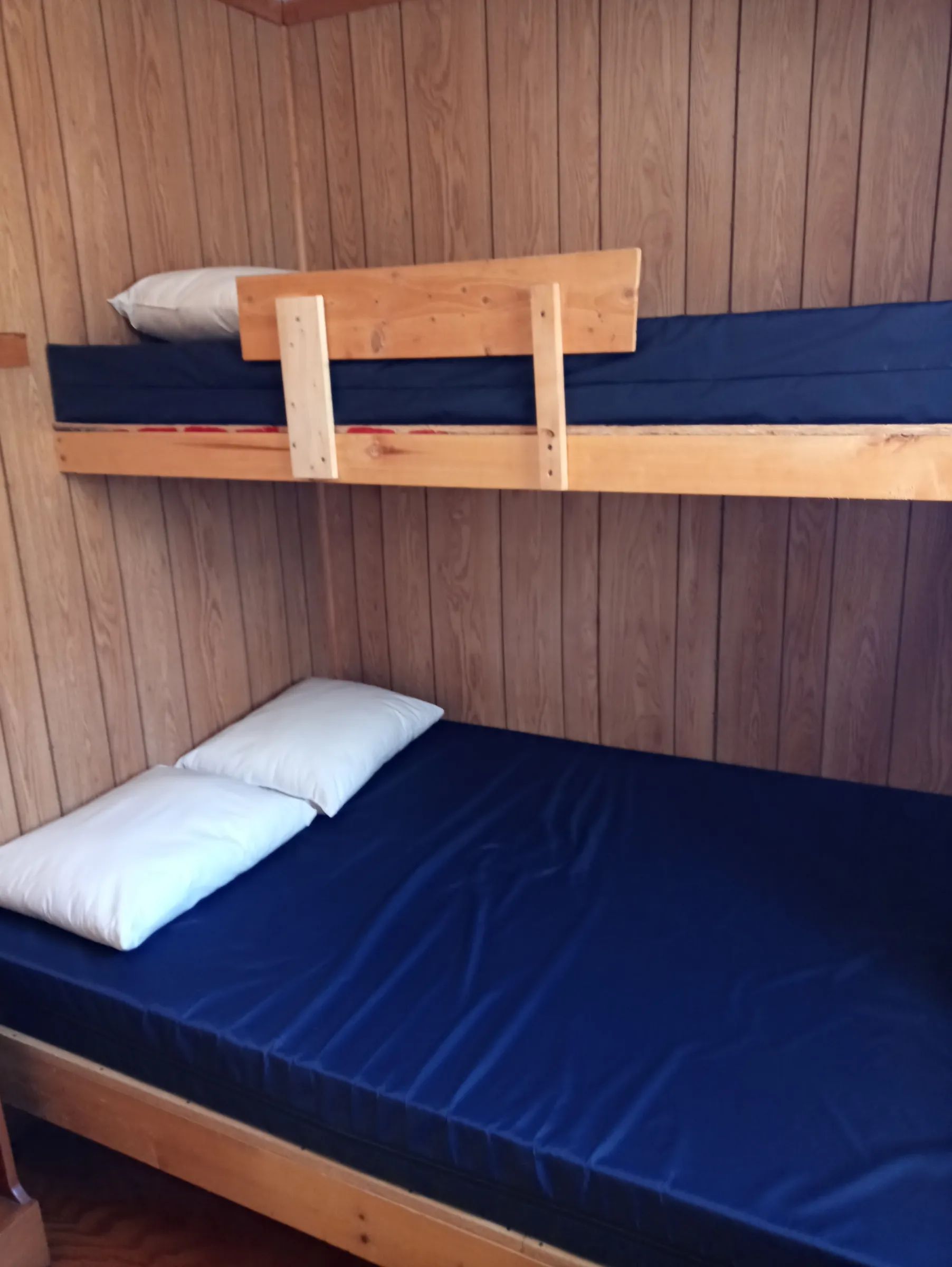 Vue sur le coin couchage en bois du chalet Le Lynx avec ses matelas et oreillers.