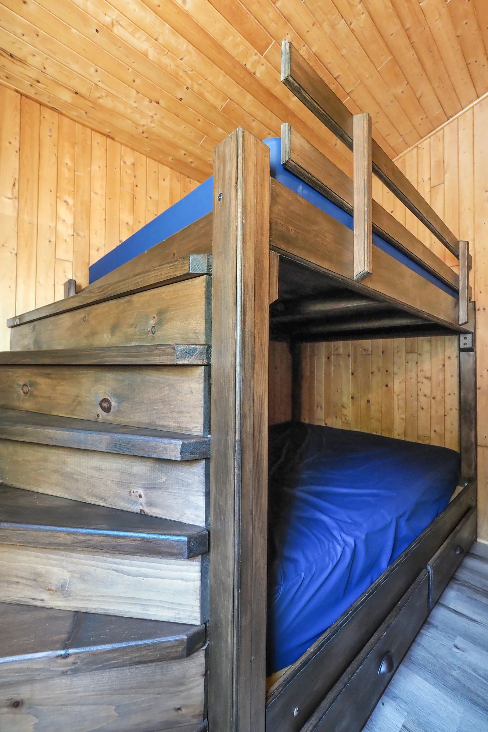 This cabin features a wooden bunk bed with integrated stairs for access.