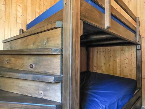 This cabin features a wooden bunk bed with integrated stairs for access.