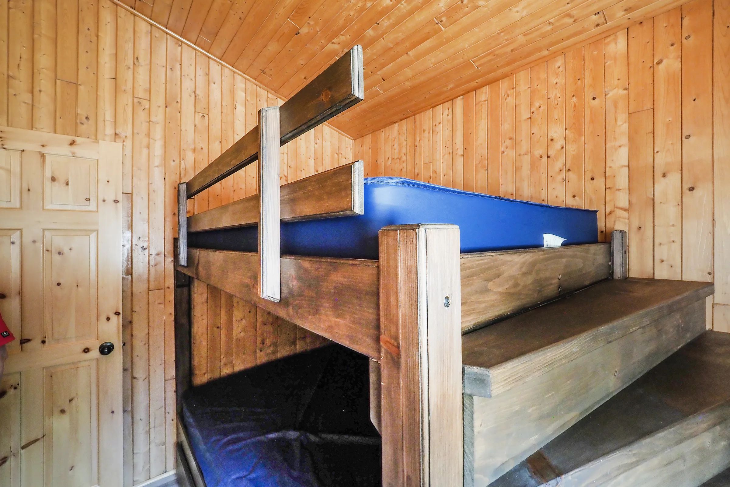 This cottage bedroom features a wooden bunk bed with blue mattresses.