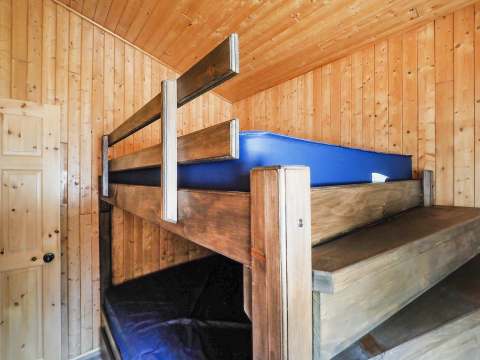 This cottage bedroom features a wooden bunk bed with blue mattresses.