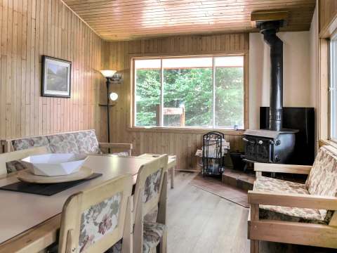 The cottage living and dining area with wood stove and forest view.