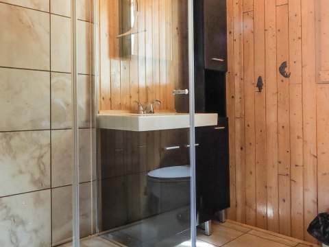View of the modern bathroom in cottage nine featuring a glass shower and wood paneling.